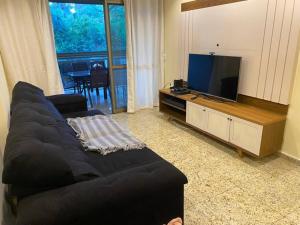 een woonkamer met een zwarte bank en een flatscreen-tv bij Apt. Luxo Cond.Mar de Conchas in Rio de Janeiro