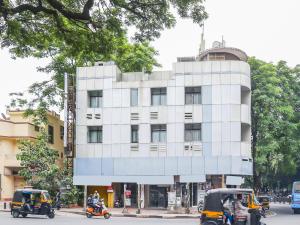 Super Collection O Hotel Pearl Near Shaniwar Wada في بيون: مبنى ابيض وامامه دراجتين