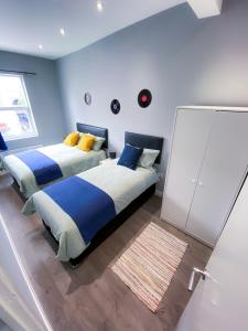 ロンドンにあるMODERN 1 BEDROOM FLAT IN WOOD GREENの青い壁のベッドルーム1室(ベッド2台付)