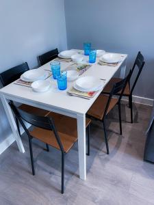 une table blanche avec des chaises, des assiettes et des verres bleus dans l'établissement MODERN 1 BEDROOM FLAT IN WOOD GREEN, à Londres