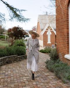 Una donna con un cappello in piedi su un marciapiede di mattoni di Flash Jacks of Gundagai a Gundagai