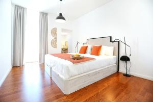 a bedroom with a large white bed with orange pillows at Xtraordinary Moments Apartment in Faro +9 photos