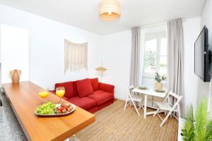 a living room with a red couch and a table with a bowl of fruit at Xtraordinary Moments Apartment in Faro