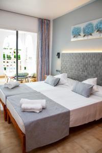 a bedroom with two beds with towels on them at Atalaya Bosque Apartamentos in Paguera