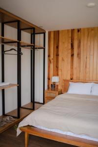 - une chambre avec un lit et un mur en bois dans l'établissement Mya Lakeview Villa Biệt Thự, à Bảo Lộc