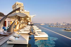 eine Reihe von Stühlen und Sonnenschirmen auf dem Dach eines Gebäudes in der Unterkunft Atlantis The Royal in Dubai