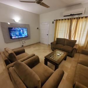 a living room with couches and a flat screen tv at Private Suite F-10 Islamabad in Islamabad