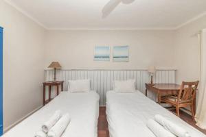 two beds in a room with a table and a chair at Tropical 1BD Hideaway near Queens Beach Fresnaye! in Cape Town