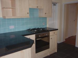 a kitchen with a stove and blue tile at Bargain rooms in Weymouth in Weymouth