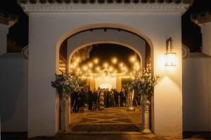 a wedding ceremony in a lit up room with people at Hacienda el Burgo in Mairena del Aljarafe