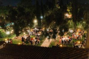 Eine Gruppe von Menschen sitzt nachts an Tischen in einem Park. in der Unterkunft Hacienda el Burgo in Mairena del Aljarafe + 48 Fotos