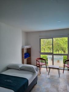 1 dormitorio con cama, sillas y ventana en Hotel Puerto Triunfo, en Doradal