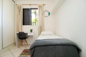 Schlafzimmer mit einem Bett, einem Schreibtisch und einem Fenster in der Unterkunft Conforto e Estilo no Centrinho da Lagoa QX6398 in Florianópolis
