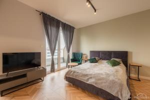 a bedroom with a bed and a flat screen tv at Horyzont Apartamenty- Studio- SAUNA&FITNESS -BAŁTYCKA 2- ŚNIADANIA in Kołobrzeg