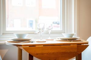 a table with two glasses and plates and bowls at Redhill Garland- 1 bed ground floor apartment by LGW Short Lets in Redhill