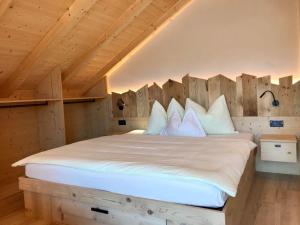 1 dormitorio con 1 cama grande con almohadas blancas en Apartments Chalet Maria, en Badia