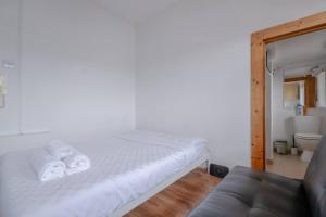 a white bedroom with a bed and a couch at Bright & Quaint Studio Flat - Hornsey! in London