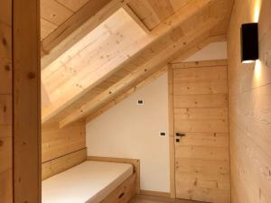 um pequeno quarto no sótão com uma cama e tectos em madeira em Apartments Chalet Maria em Badia