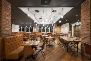 um restaurante com mesas e cadeiras e um lustre em Holiday Inn Leeds Brighouse, an IHG Hotel em Brighouse