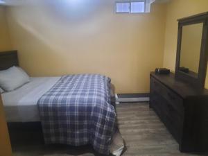 1 dormitorio con cama, tocador y espejo en One bedroom basement suite with private living room and laundry. en Brampton