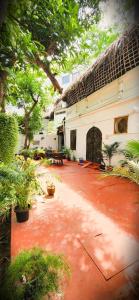 a courtyard of a building with trees and a red floor at Angel Heritage Home - Serenity Beach, Pondicherry. in Puducherry