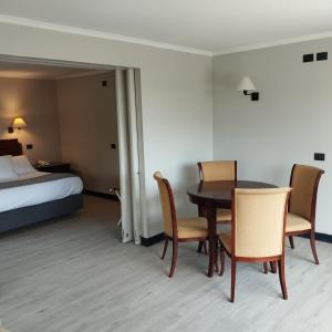 ein Hotelzimmer mit einem Tisch, Stühlen und einem Bett in der Unterkunft Hotel Villa el Descanso in Curicó