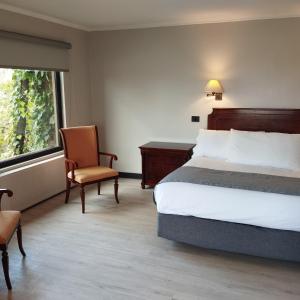 Hotel Villa el Descanso في كوريكو: غرفة نوم بسرير وكرسي ونافذة