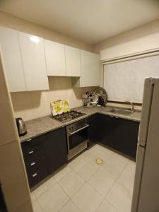 uma cozinha com armários brancos e um forno com placa de fogão em Rimini Furnished Apart. em Amã