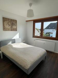 Un dormitorio con una cama en una habitación con ventana. en Appartement de 115m2 à 10 min de Strasbourg & 25 min d'Europa Park !, en Illkirch-Graffenstaden