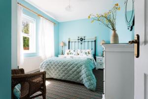 ein blaues Schlafzimmer mit einem Bett und einem Stuhl in der Unterkunft Brookhall Cottages in Lisburn