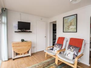 sala de estar con 2 sillas y TV de pantalla plana en Sundowner en Caernarfon