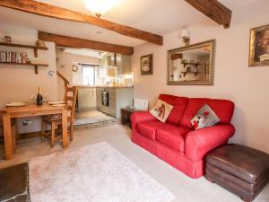 a living room with a red couch and a table at Moorside Cottage in Oxenhope