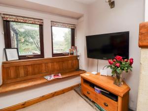 een woonkamer met een televisie en een vaas met bloemen bij Moorside Cottage in Oxenhope