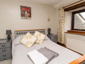 a bedroom with a white bed with pillows and a window at Moorside Cottage in Oxenhope