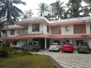 una casa con coches aparcados delante de ella en Somatheertham Panchakarma Resort en Kovalam