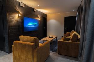 a living room with two chairs and a tv on a wall at Royal Roi Apartments in Rovaniemi