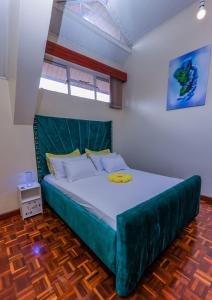 a large bed with a green headboard in a room at Cosy and accessible 1BR penthouse with terrace in Nairobi