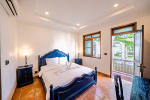 um quarto com uma cama azul e uma janela em Pitaloka Hotel Sanur By DeWizZ Management em Sanur