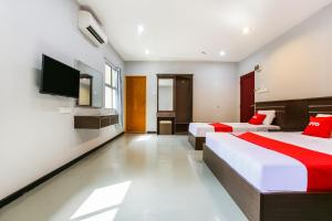 um quarto de hotel com duas camas e uma televisão de ecrã plano em OYO 89660 Raudhah Inn Hotel em Kampong Bukit Kechil