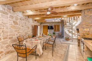a dining room with a table and chairs and a stone wall at House Hidden Beauty in Tribunj