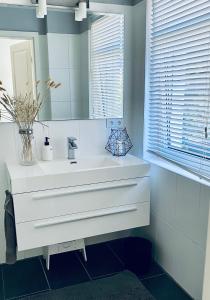 La salle de bains est pourvue d'un lavabo blanc et d'un miroir. dans l'établissement Beautiful House in Blankenese, à Hambourg