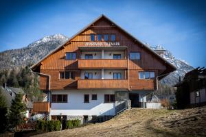 a large wooden building on a hill with mountains in the background at Apartments Telemark Kranjska Gora in Kranjska Gora