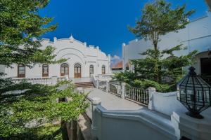 uma casa branca com uma escadaria e árvores em Pitaloka Hotel Sanur By DeWizZ Management em Sanur