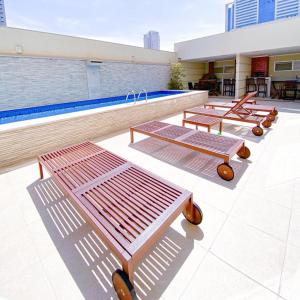 a row of benches next to a swimming pool at Elegante apto de 2/4 2004 in Goiânia