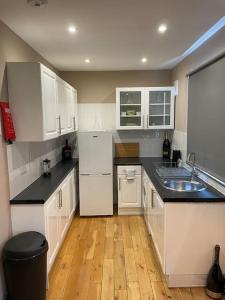 a kitchen with white cabinets and a wooden floor at A Lovely 1 Bedroom Flat / Modern-Cosy in London