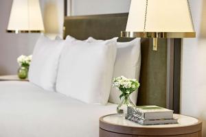 Una cama con almohadas blancas y una mesa con libros. en London Hilton on Park Lane en Londres