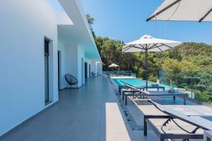 an outdoor swimming pool with benches and an umbrella at Villa Anthelia in Pentátion