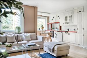 a living room with a white couch and a kitchen at Queen's Cave By Staysville in Stavanger