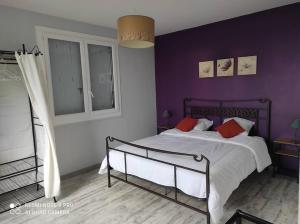 ein Schlafzimmer mit einem großen Bett mit lila Wänden in der Unterkunft Haut de villa : véranda, terrasse, vue piscine in Thiviers