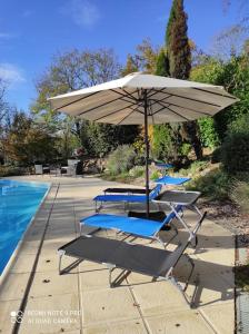 zwei Liegestühle und ein Sonnenschirm neben einem Pool in der Unterkunft Haut de villa : véranda, terrasse, vue piscine in Thiviers